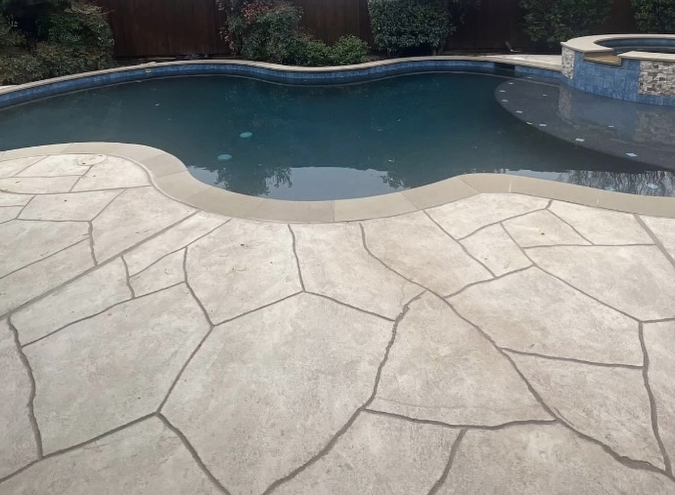After deck recoating: warm stone-pattern finish around the pool and spa