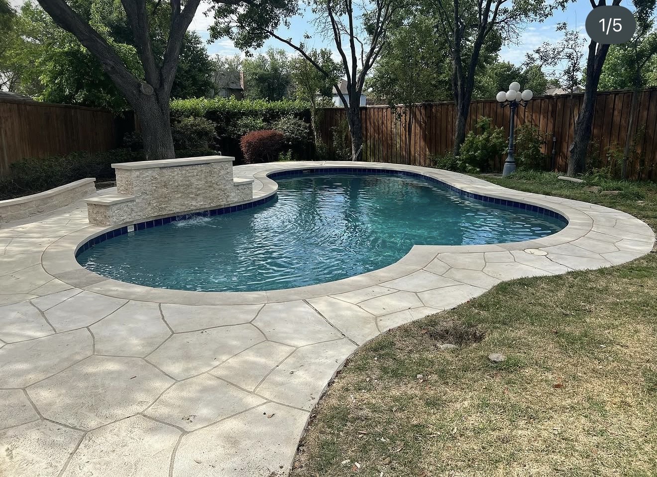 After renovation: cream stone-pattern deck around the remodeled pool