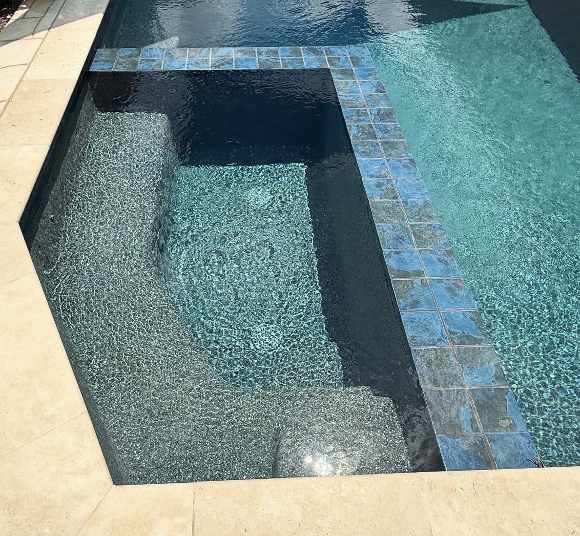 After construction: finished integrated spa with blue tile, underwater seating and stone coping