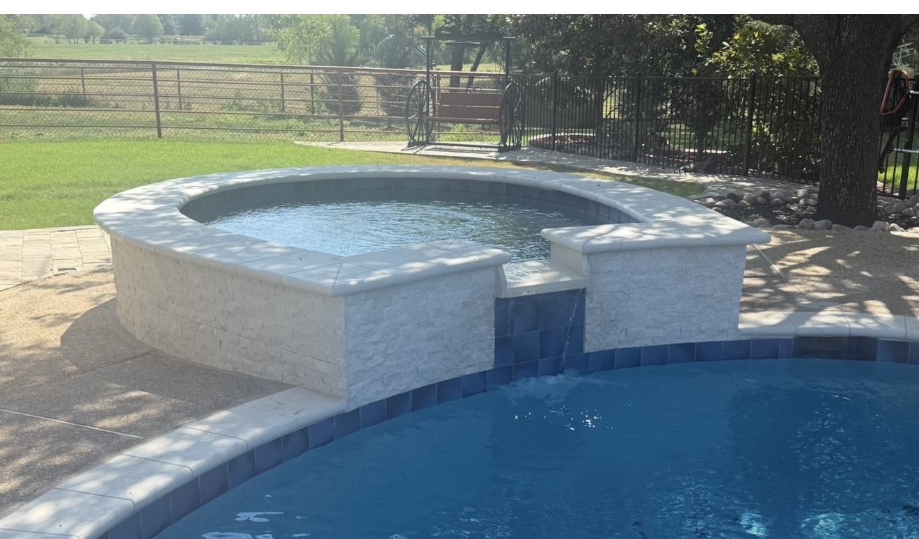 After construction: completed raised round spa with light stone veneer, coping and a spillway into the pool